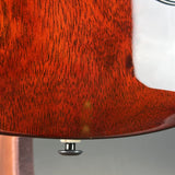 Close-up detail of an electric guitar body showing the glossy reddish-brown wood grain finish and a small metal hardware piece near the bottom edge.