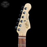 Close-up of the headstock of a guitar against a black background, showing the brand name 'CH' and model 'Legacy' with six tuning pegs and a light natural wood neck.