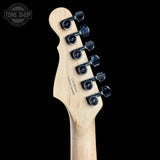 Close-up of the headstock of an electric guitar, showing a natural maple wood neck with six black tuning pegs and 'Gibson' branding printed on the back, set against a solid black background.