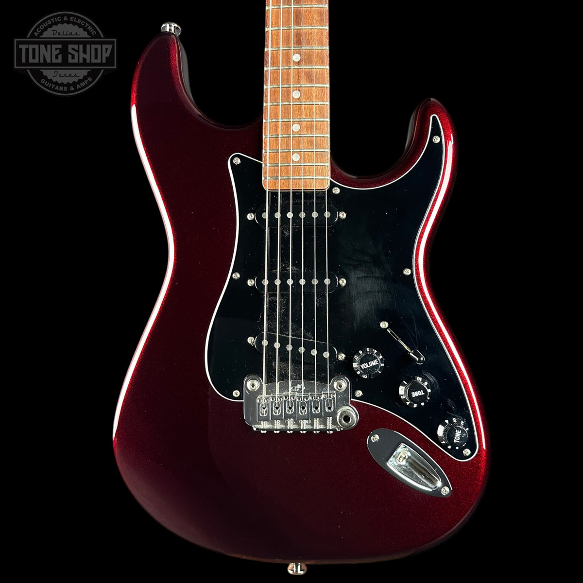 A classic electric guitar with a glossy dark red body, black pickguard, maple neck, and chrome hardware, shown against a solid black background with a Tone Shop watermark in the top left corner.