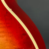 Close-up of a red guitar with a white binding on a dark background
