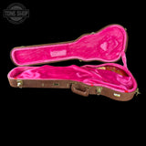 Guitar case with pink interior on a black background, featuring 'Tone Shop' logo.