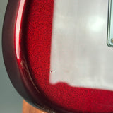 Close-up of a glossy red electric guitar body showing the edge of the finish, a white pickguard, and part of a silver control plate.