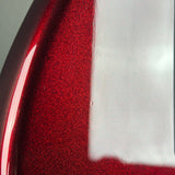 Close-up of a glossy red metallic surface with fine glitter texture and a white reflective highlight.