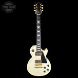 A cream-colored electric guitar with a black pickguard and gold hardware, shown against a solid black background. A 'TONE SHOP' watermark is visible in the top-left corner.