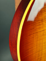 Close-up of a guitar's wooden neck with a yellow binding on a dark background