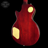Red electric guitar with gold hardware on a black background, featuring 'Tone Shop' logo.