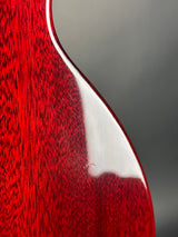 Close-up of a red guitar neck with a white pickguard on a gray background