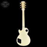 A cream-colored electric guitar shown from the back against a solid black background, featuring gold tuning pegs and a white branded Tone Shop watermark in the upper left corner.