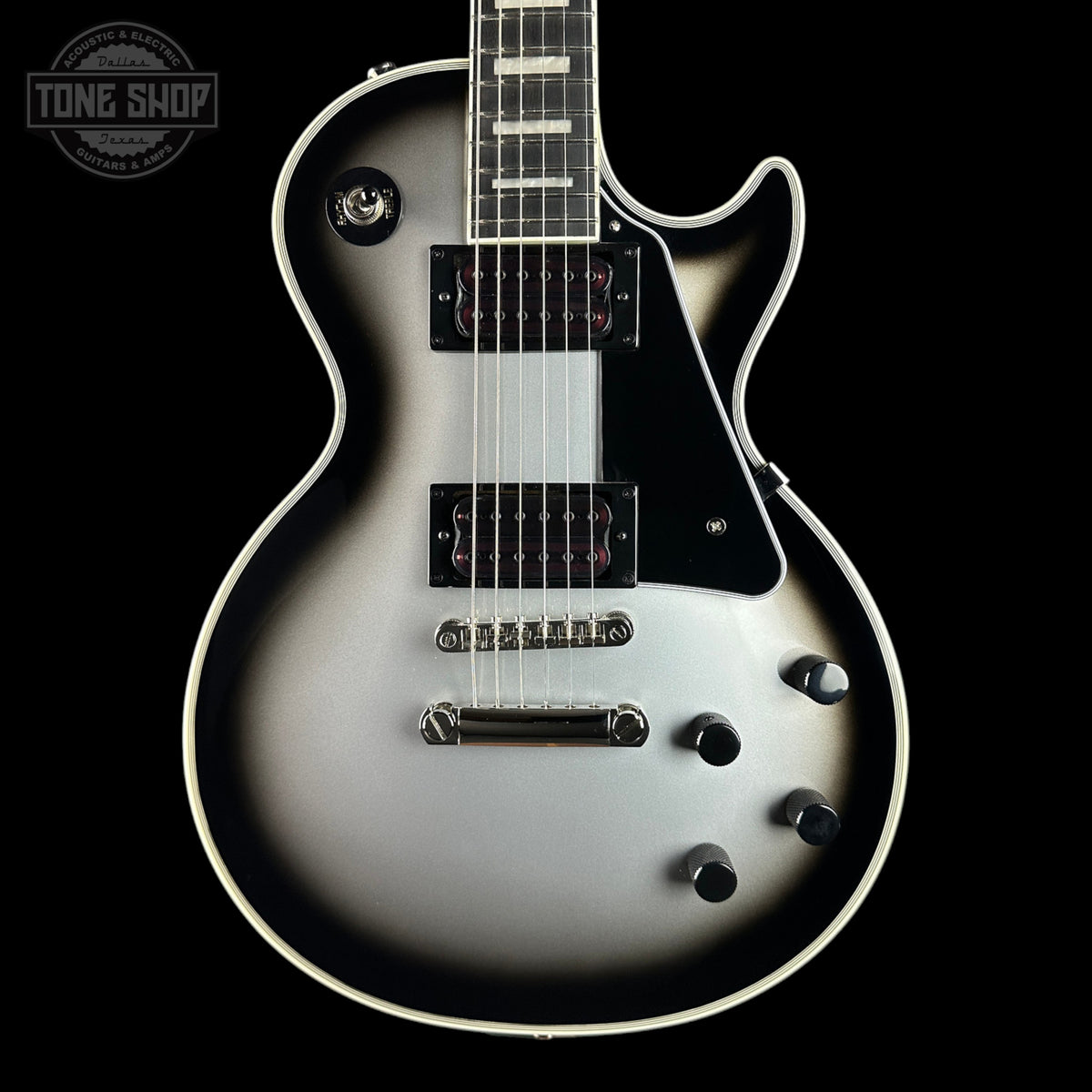 A double-cutaway electric guitar with a silver-to-black gradient finish, black pickguard, and chrome hardware, shown against a solid black background with a Tone Shop logo in the top-left corner.