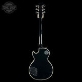 A black electric guitar shown from the back against a solid black background, featuring a glossy black finish, white binding, and silver hardware. A 'TONE SHOP' watermark is visible in the top-left corner.