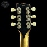 Close-up of a guitar's headstock with tuning pegs on a black background, featuring the Tone Shop logo.