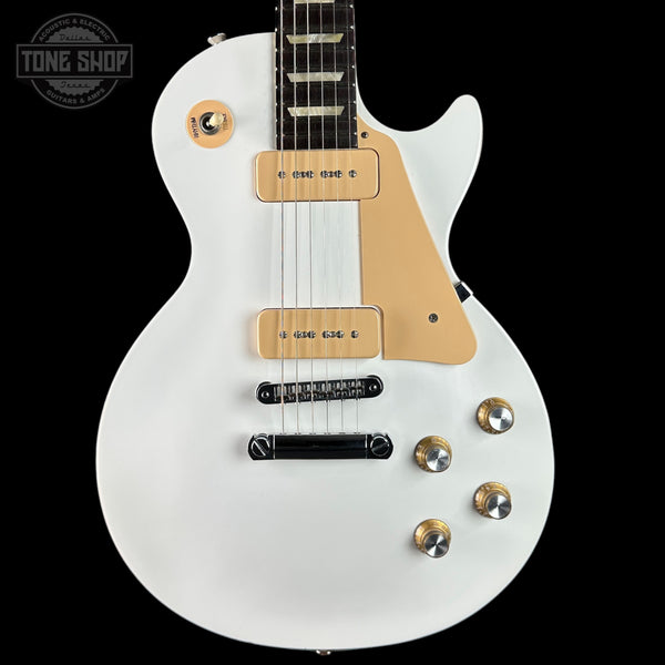 White electric guitar with a black pickguard on a black background, featuring the 'Tone Shop' logo.