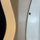 Close-up detail of an electric guitar body showing the cream-colored maple top edge, a white pickguard with a black double border, and a single black control screw.