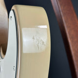 Close-up of a cream-colored electric guitar body showing a glossy finish with a noticeable scuff and paint damage on the upper bout section.