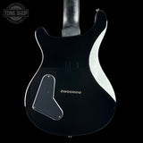 The back of a black electric guitar body with a white side stripe, shown against a black background. A Tone Shop watermark is visible in the top-left corner.