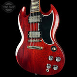 Red electric guitar with a black pickguard on a black background, featuring the Tone Shop logo.