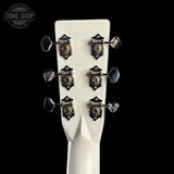 Close-up of a guitar headstock with tuning pegs on a black background, featuring the Tone Shop logo.