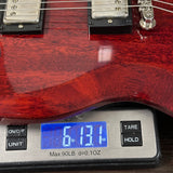 Guitar being weighed on a digital scale with a wooden finish.