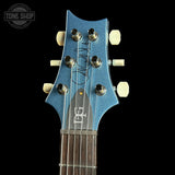 Close-up of a guitar headstock with a blue finish and 'Tone Shop' branding.