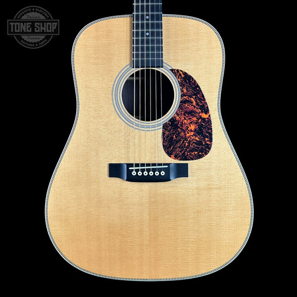 Acoustic guitar with a flame maple top on a black background, featuring the Tone Shop logo.