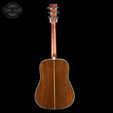 Back view of a wooden acoustic guitar on a black background with 'Tone Shop' logo.