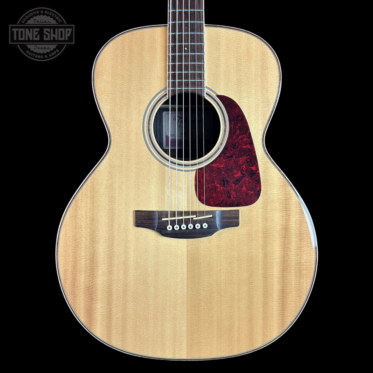 Acoustic guitar with a visible brand logo on a black background