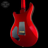 Red electric guitar with a black pickguard on a black background, featuring 'Tone Shop' branding.