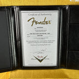 Fender certificate of authenticity in a black leather holder on a yellow surface
