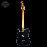 Black electric guitar with a visible brand logo on a black background