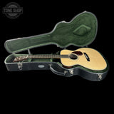 Acoustic guitar in a green hard case with 'Tone Shop' logo.