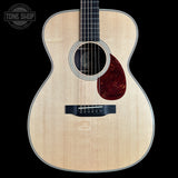 Acoustic guitar with a dark brown soundhole on a black background, featuring 'Tone Shop' logo.