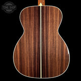 Back view of a wooden acoustic guitar with a visible brand logo in the corner.