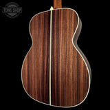 Close-up of a wooden acoustic guitar back with 'Tone Shop' logo.