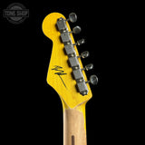 Close-up of the headstock of a Fender electric guitar with a bright yellow finish, silver tuning pegs, and a black script logo on a black background. A Tone Shop watermark is visible in the top left corner.