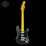 A black electric guitar with a bright yellow maple neck and headstock, photographed against a solid black background. A circular 'TONE SHOP' watermark is visible in the top-left corner.
