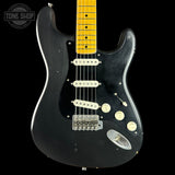A black electric guitar with a yellow maple neck, featuring a black pickguard, cream-colored knobs and bridge, and a chrome headstock cover, shown against a black background with a Tone Shop logo in the top left corner.