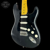 A black electric guitar with a yellow maple neck, featuring a black pickguard, chrome hardware, and a Tone Shop logo overlay in the top left corner.