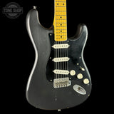 A black Stratocaster-style electric guitar with a yellow maple neck, cream pickups, and chrome hardware, shown against a black background with a Tone Shop watermark in the upper left.