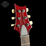 Close-up of a red guitar headstock with tuning pegs on a black background, featuring the Tone Shop logo.