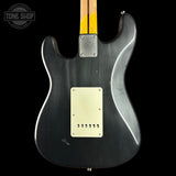 The back of a black electric guitar with a silver metallic finish, a cream-colored pickguard, and a yellow maple neck visible at the top, set against a solid black background.