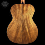 Close-up of a wooden acoustic guitar back with 'Tone Shop' logo.