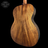 Close-up of a wooden acoustic guitar body with 'Tone Shop' logo.