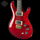 Red electric guitar with a black background, featuring the Tone Shop logo.