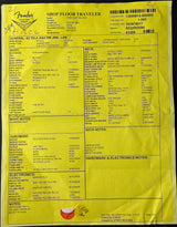 A yellow printed shop floor traveler tag with black text, barcodes, and sections for body notes, hardware, electronics, and notes, photographed flat against a dark background.