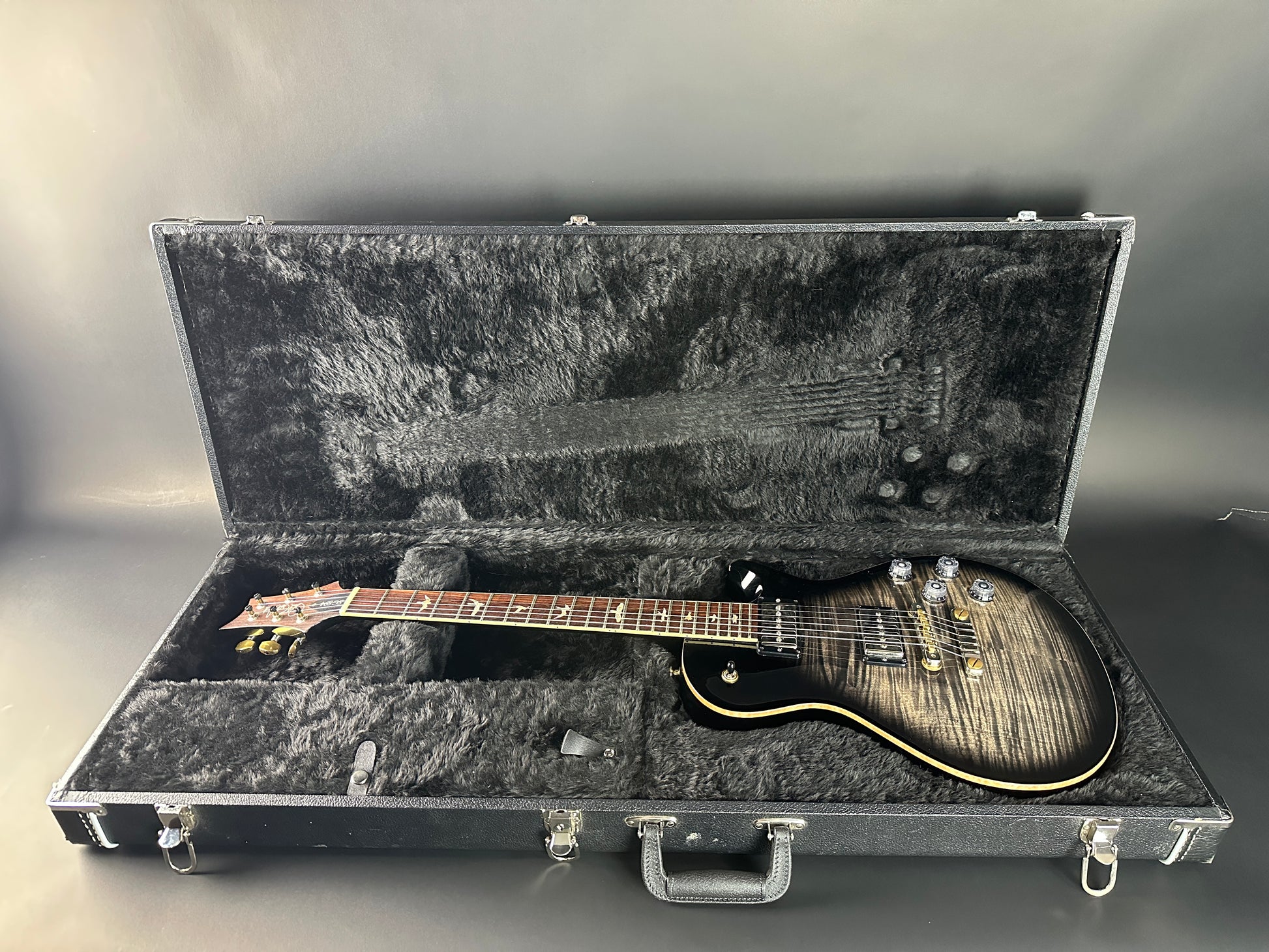 Guitar in an open hard-shell case on a gray background