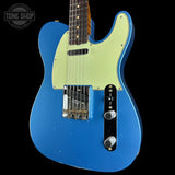 A blue electric guitar with a pale yellow-green pickguard, shown against a black background. A Tone Shop watermark is visible in the top left corner.