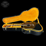 Acoustic guitar in an open hardshell case with 'Tone Shop' logo.