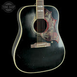 Black acoustic guitar with floral design on a black background, featuring the Tone Shop logo.