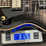 Black electric guitar on a digital scale displaying weight